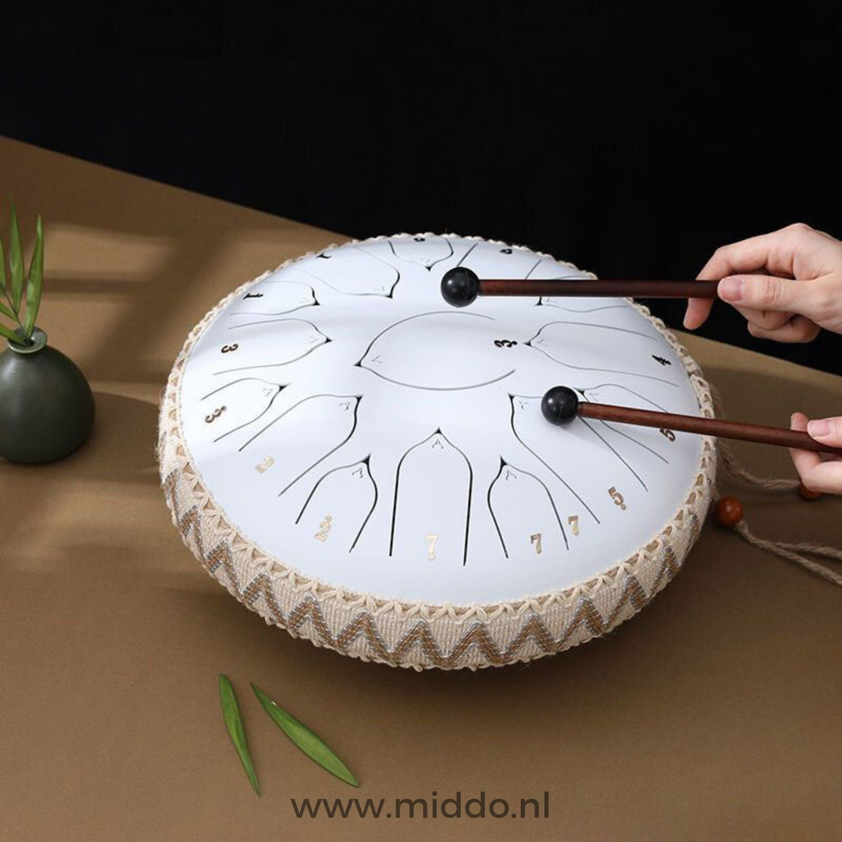 Hände spielen ein weißes Harmonii KlankOase Steel Tongue Drum mit Schlägeln
