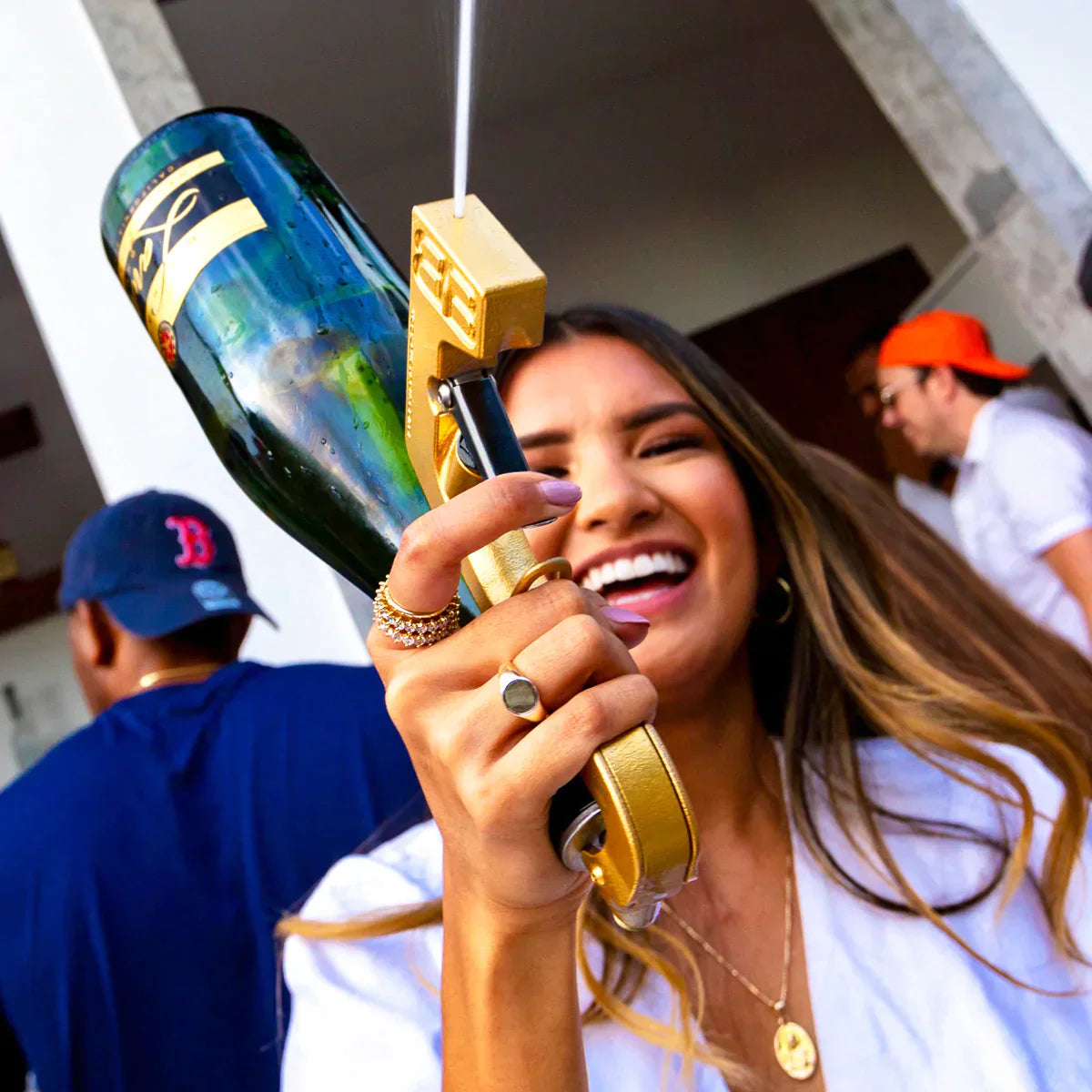 Lächelnde Frau auf einer Party mit goldfarbener Trinkpistole und Champagnerflasche
