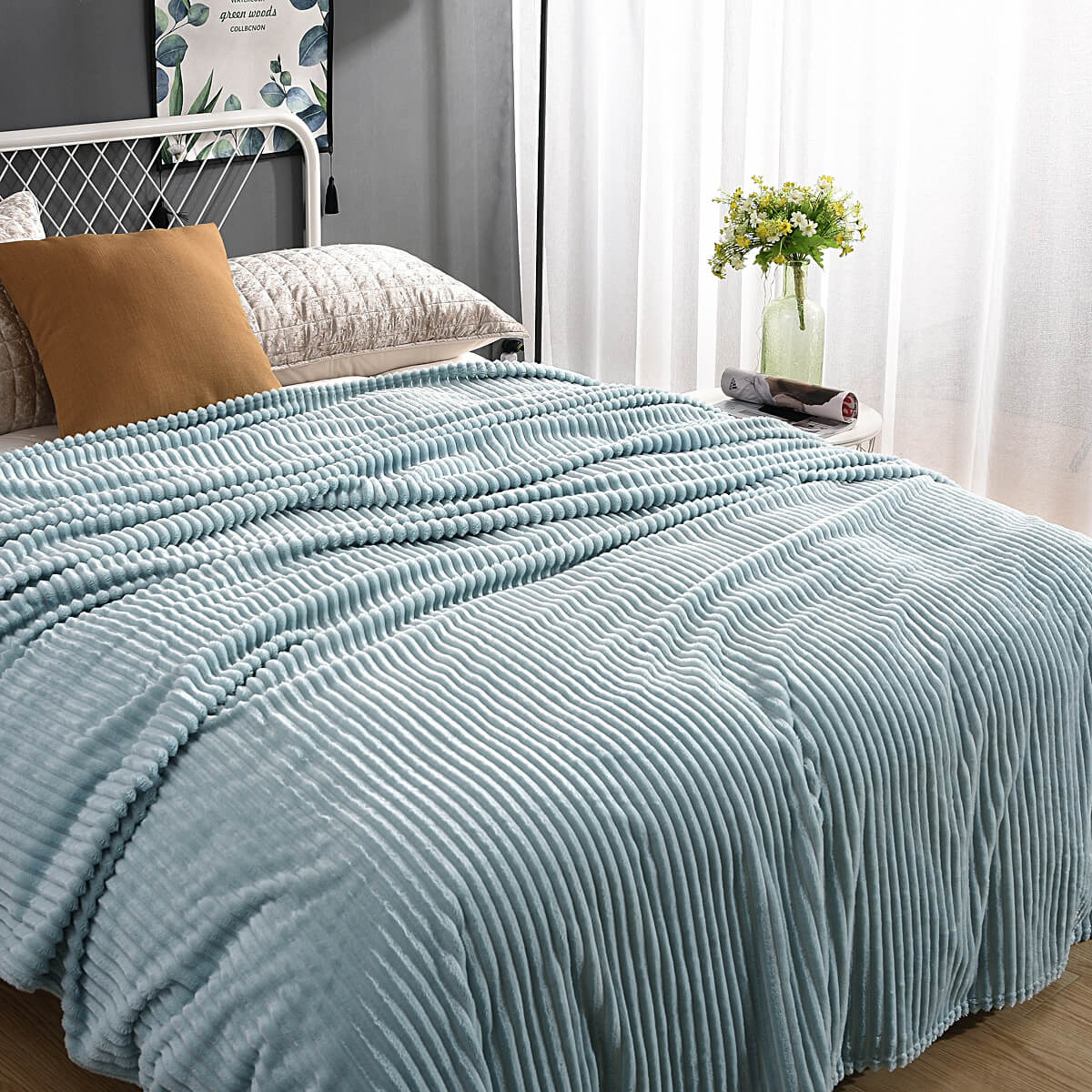 Helle blaue Samt-Fleece-Decke auf einem gemachten Bett mit Kissen