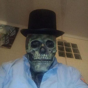Person mit realistischer Totenkopfmaske und schwarzem Zylinder als gruseliges Halloween-Kostüm