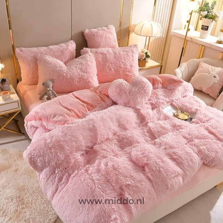 Foto von 5 Sets von hellrosa flauschiger Fleece-Bettwäsche mit gratis Herzkissen, ordentlich auf einem Bett mit einem kleinen grauen Kuschelbär arrangiert.