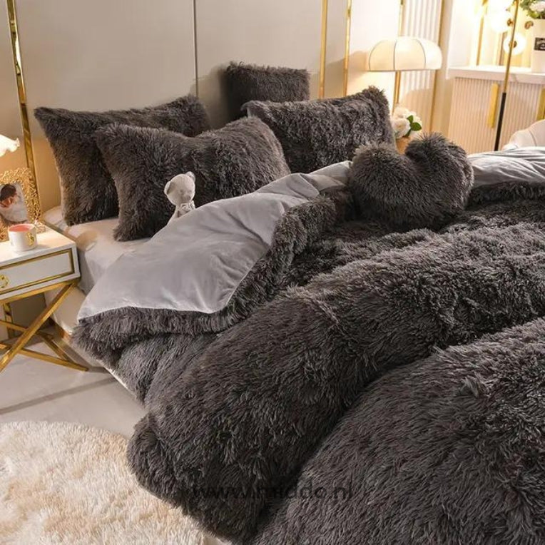 Foto von 5 Set Schwarze flauschige Fleece-Bettwäsche mit kostenlosem Herz-Kissen, schön auf dem Bett mit einem kleinen Kuschelbärchen arrangiert.