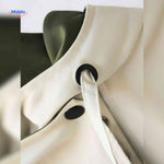AquaShell Jas – Detailaufnahme in Creme mit grünen Knöpfen. Besuchen Sie www.middo.de.