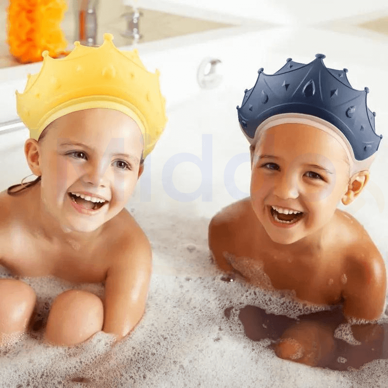 Zwei lachende Kinder in der Badewanne mit gelben und blauen krönchenförmigen Badehüten.