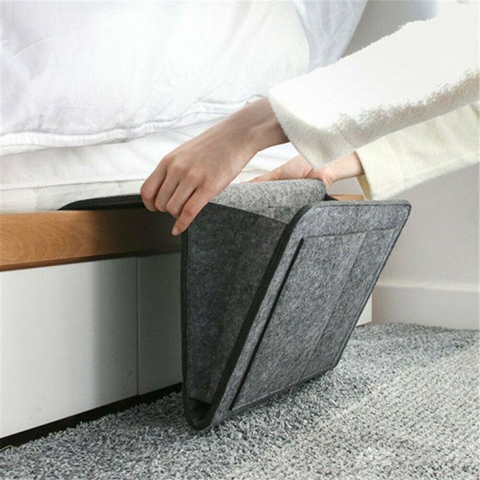 Eine Dame hängt die graue BedCaddy an die Seite eines weißen Bettes.