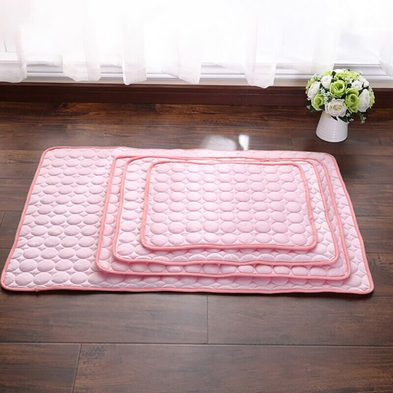 Roze Coolmat in allen Größen für Haustiere auf einem braunen Fliesenboden.