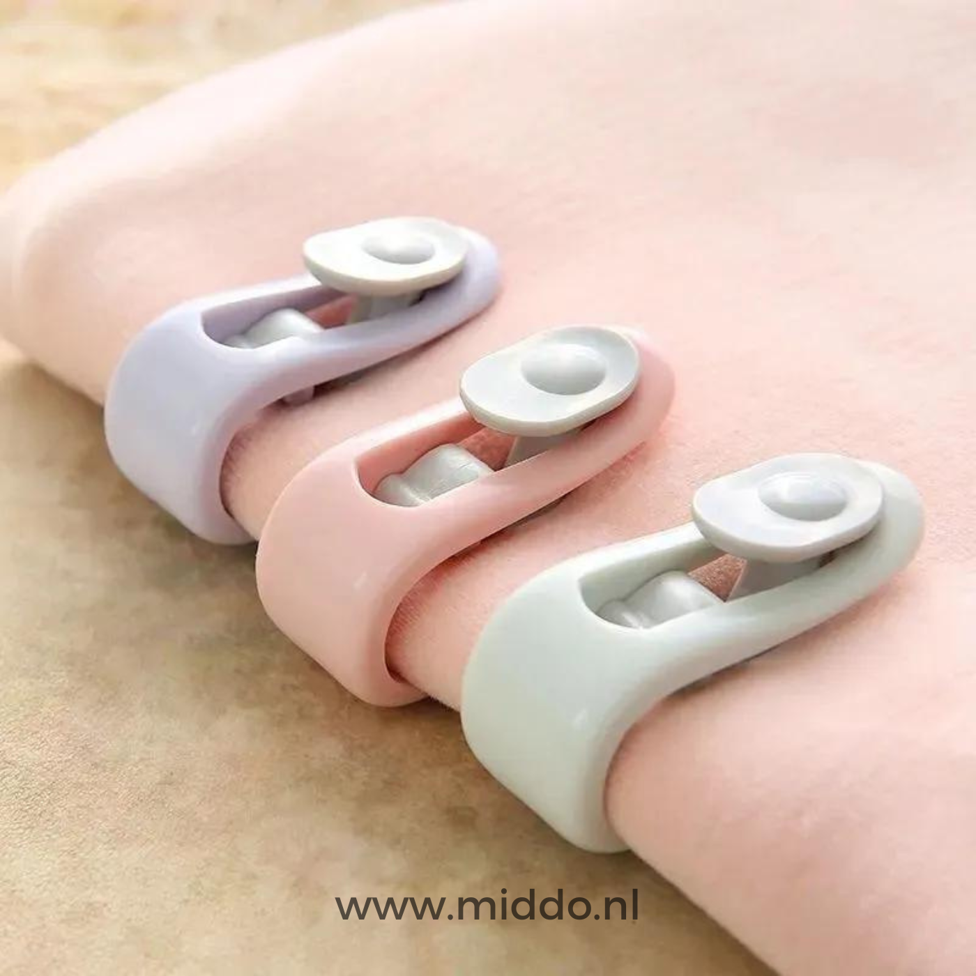 Drei Bettdeckenklammern in Pastellfarben auf einer Decke
