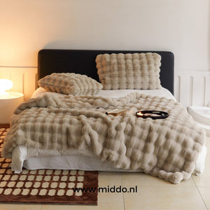 Beige flauschige toskanische Winterdecke auf dem Bett in einem stimmungsvollen Raum