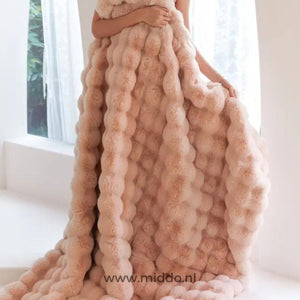 Frau in rosa flauschiger Decke am Fenster