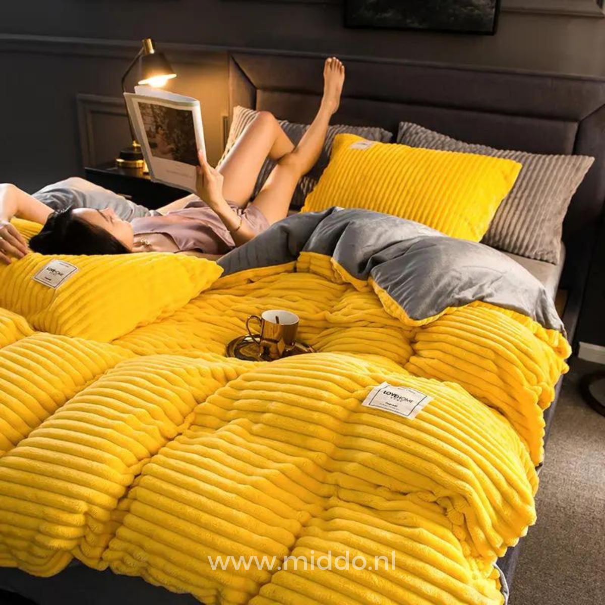 Frau liegt auf dem Bett mit einer Zeitschrift auf einem gelben Bettbezug.