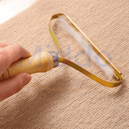 Hand mit FurBuster entfernt Fusseln von Stoffoberflächen.