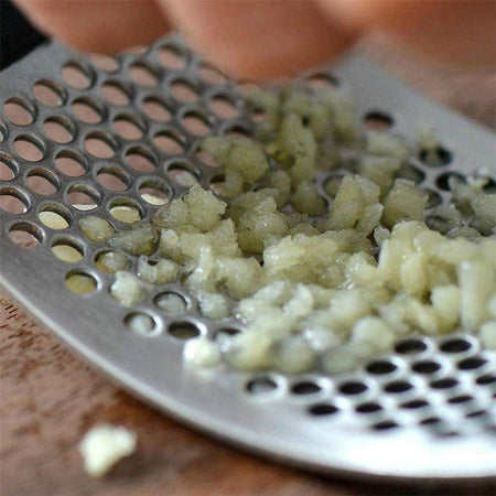 Nahaufnahme von gepresstem Knoblauch durch die HandyPress Edelstahl-Knoblauchpresse.