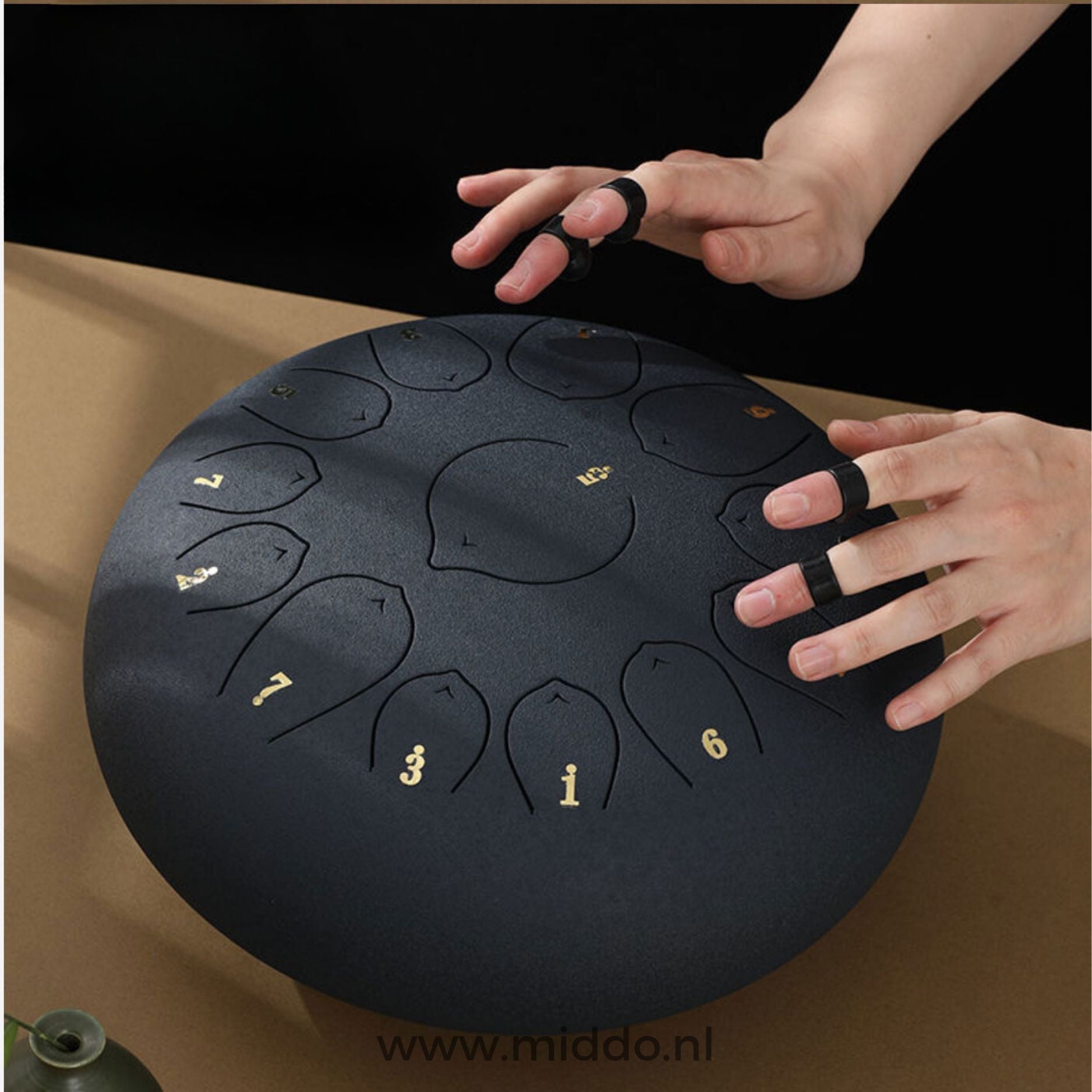 Hände spielen eine schwarze Harmonii KlankOase Steel Tongue Drum mit Fingernägeln.