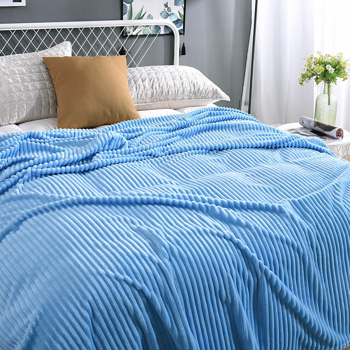 Himmelblaue, samtartige Fleece-Decke auf einem frisch betten gemachten Bett.