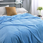 Himmelblaue, samtartige Fleece-Decke auf einem frisch betten gemachten Bett.