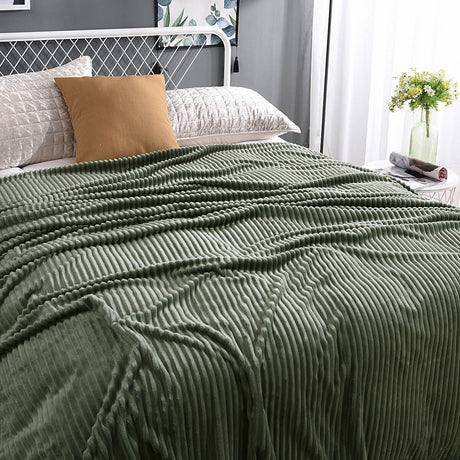 Grüne, samtige Fleece-Decke auf einem gemachten Bett