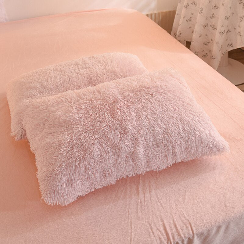 Foto von 2 rosa flauschigen Fleece-Kissenbezügen auf einem Bett.