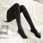 Schwarze Strumpfhose mit geschlossenen Zehen, Dame sitzt auf dem Bett.