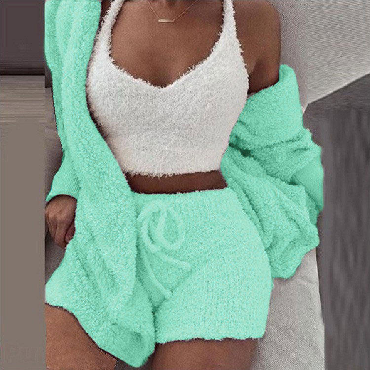 Frau in mintfarbener SheCutie Comfy-Set mit Shorts, Top und Cardigan sitzt auf der Couch.