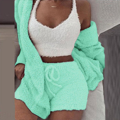 Frau in mintfarbenem SheCutie Comfy-Set mit Shorts, Top und Cardigan sitzt auf der Couch