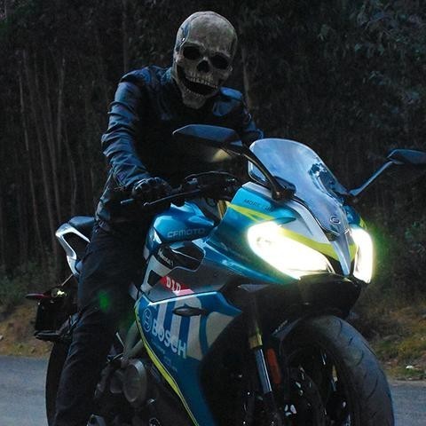 Person mit Totenkopfmaske auf Motorrad nachts