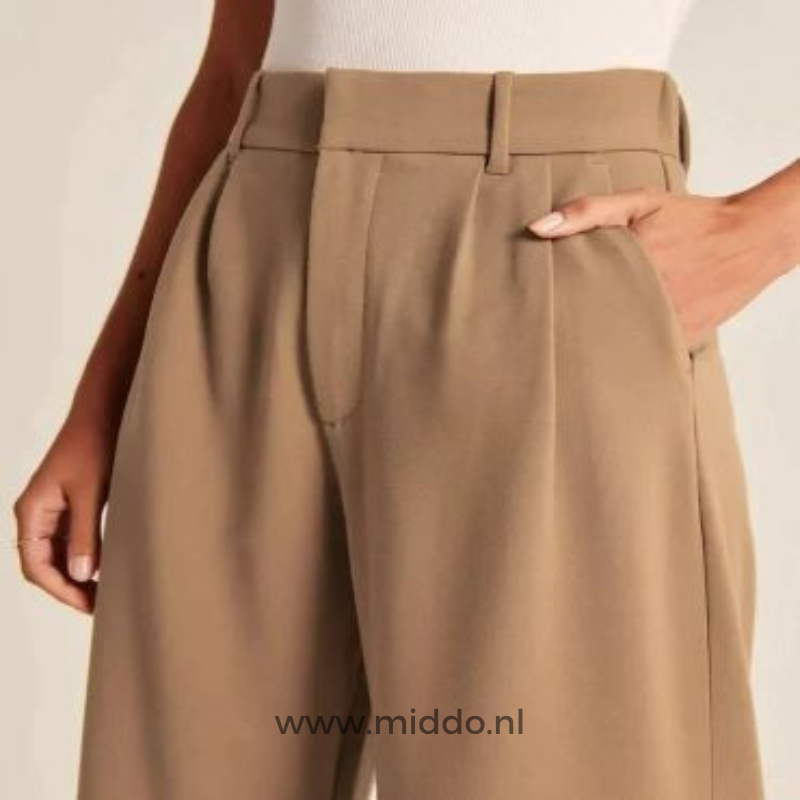 Foto einer Frau in einer braunen, weiten Hose, die von der Hüfte aus betrachtet wird und ihre Hand in der Seitentasche hat.