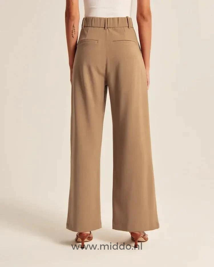 Diese Dame zeigt die Rückseite der braunen Weitformat-Hose mit 2 Gesäßtaschen.