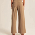 Diese Dame zeigt die Rückseite der braunen Weitformat-Hose mit 2 Gesäßtaschen.