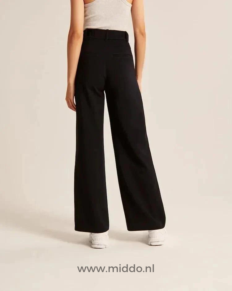 Eine Frau in weißen Sportschuhen präsentiert die schwarze, weite Hose.