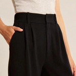 Foto einer Frau in einer schwarzen, weiten Hose, die von der Taille aus gesehen wird und ihre Hand in der Seitentasche hat.