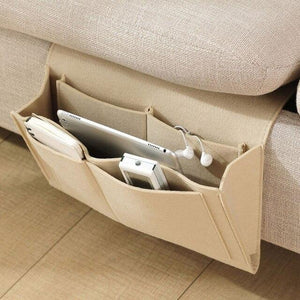 Beige BedCaddy, der an der Seite einer beigen Couch hängt, mit einem iPad und einem Telefon darin