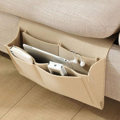 Beige BedCaddy, der an der Seite einer beigen Couch hängt, mit einem iPad und einem Telefon darin