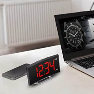Digitale Wecker mit roter LED-Zeit neben einem Laptop