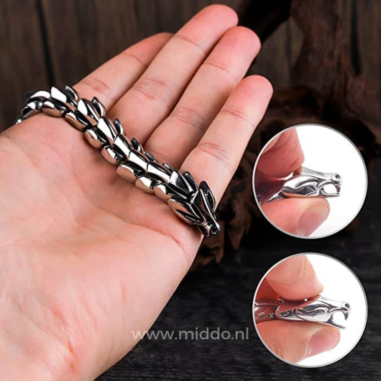 Hand hält ein silbernes Drachenarmband, Detailaufnahme des Drachenkops und der Glieder.