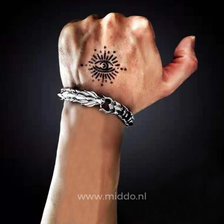 Hand mit Tätowierung trägt silberne Drachenarmband