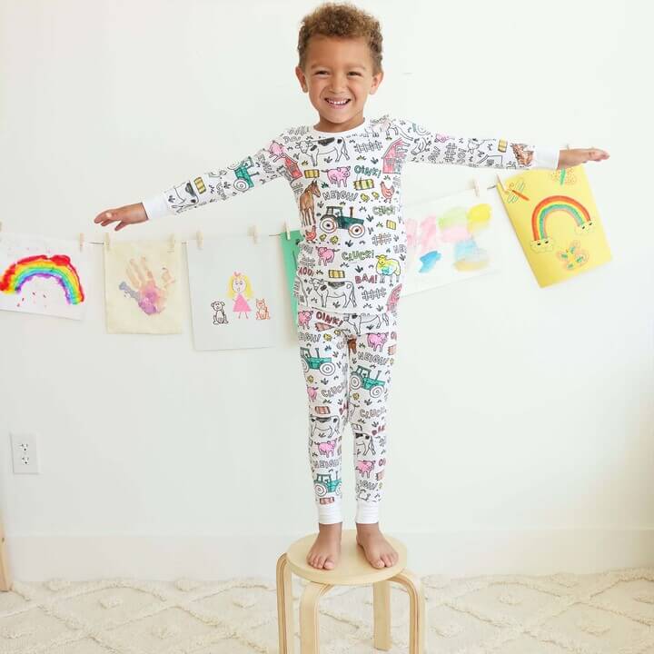 Fröhlicher Junge trägt einen bunten Bauernhof-Pyjama.