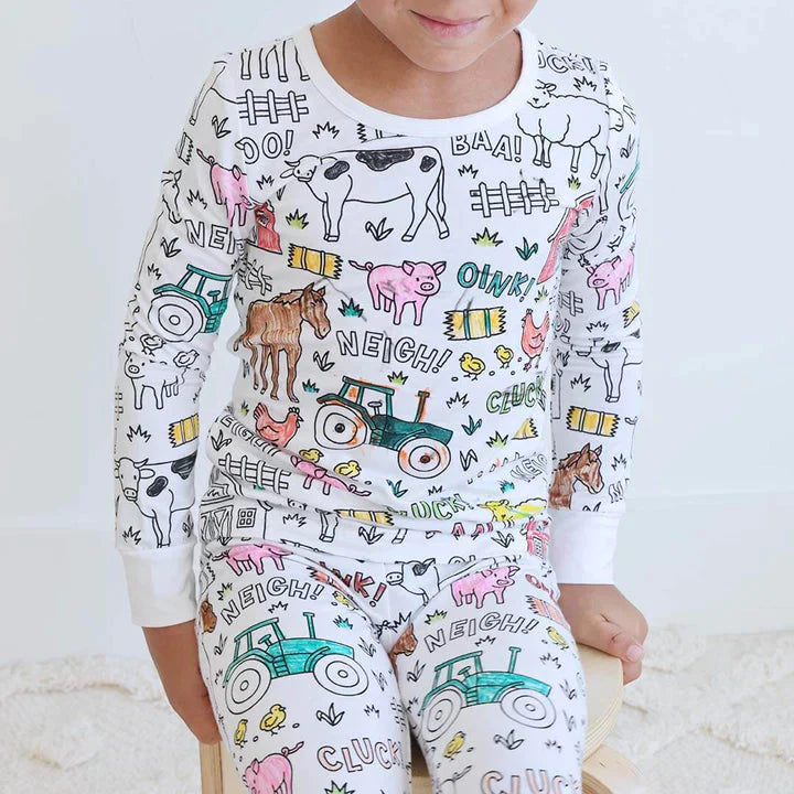 Junge trägt einen bunten Bauernhof-Pyjama.