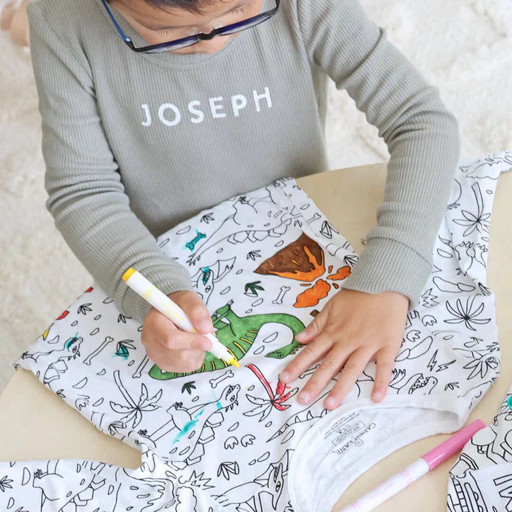 Junge färbt einen anmalbaren Dinosaurier-Pyjama aus.