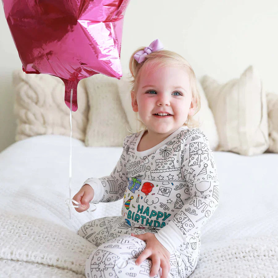Mädchen trägt einen einfärbbaren Geburtstagspyjama mit Ballons.