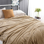 Beige Samt-Fleece-Decke auf einem Bett mit Kissen und Blumenvasen