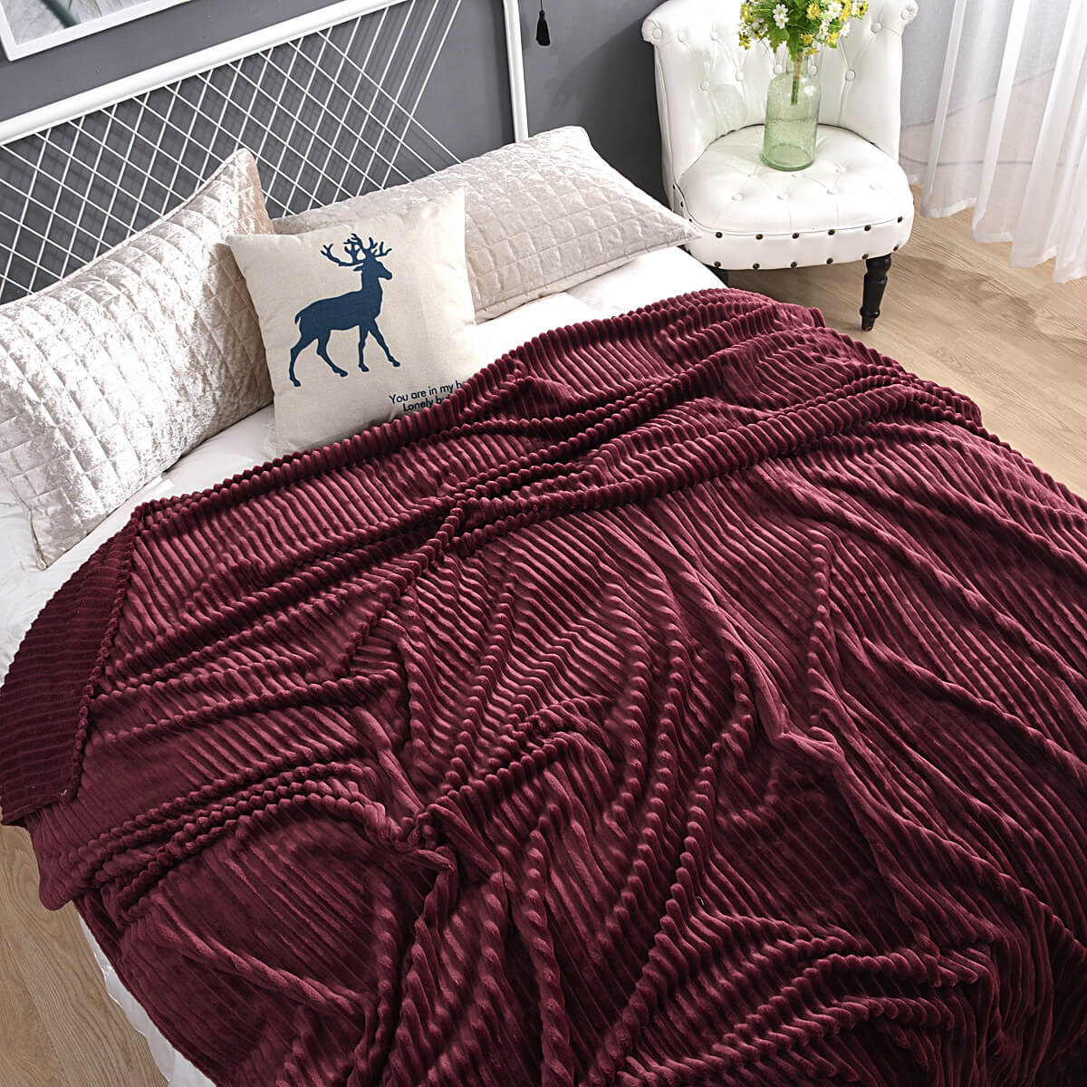 Dunkelrotes, samtiges Fleece-Decke auf einem Bett mit Rentierkissen