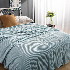 Helle blaue Samt-Fleece-Decke auf einem gemachten Bett mit Kissen