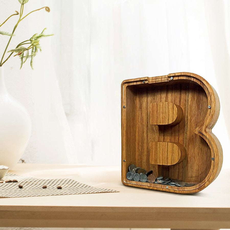 Hölzerne Spardose in Form des Buchstabens B, gefüllt mit Münzen.