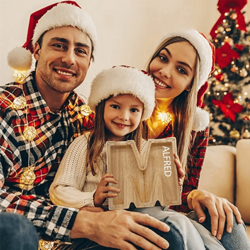 Familie mit Holz-Sparschwein Buchstabe M während Weihnachten.