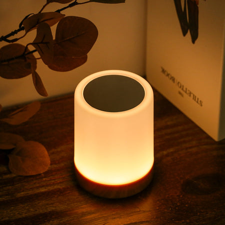 Stimmungsvolle Nachttischlampe auf hölzernem Tisch bei Pflanzen