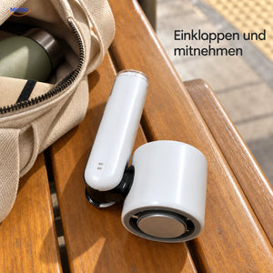 Palmora faltbarer Handventilator: weißes zusammengeklapptes Modell neben einer Reisetasche.