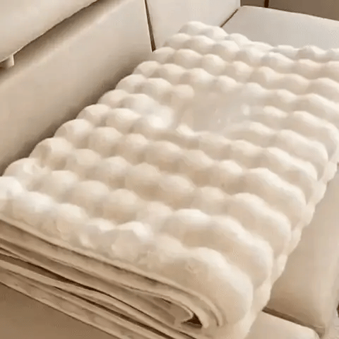 Gefaltener beiger Möbelbezug auf einem beigen Sofa