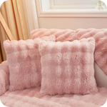 Rosa Plüschkissen und Decke auf einer Bank bei einem Fenster