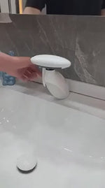 Penguino Wasserhahn in Weiß am Waschbecken, eine Hand öffnet den Wasserstrahl