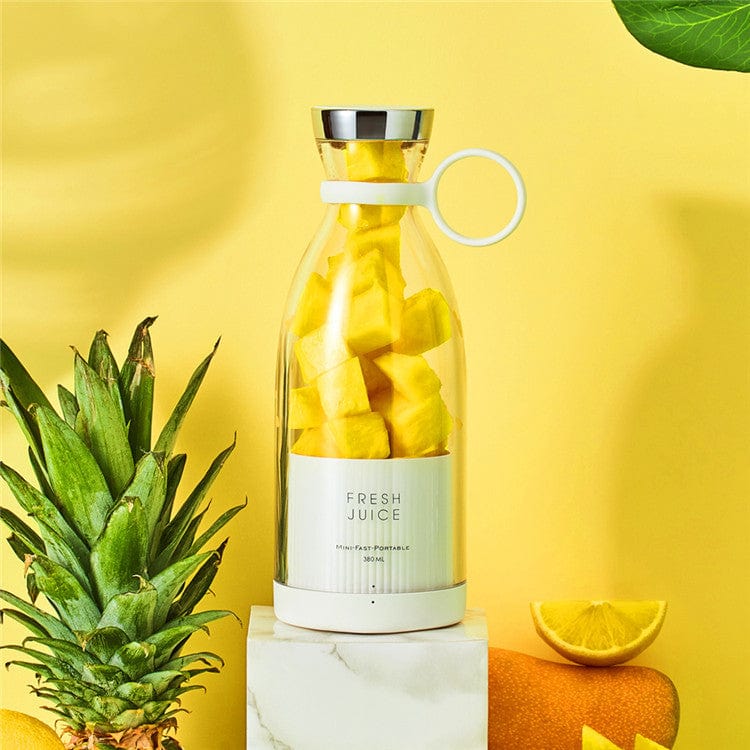 Drahtloser Mixer, gefüllt mit Ananas und umgeben von Obst.